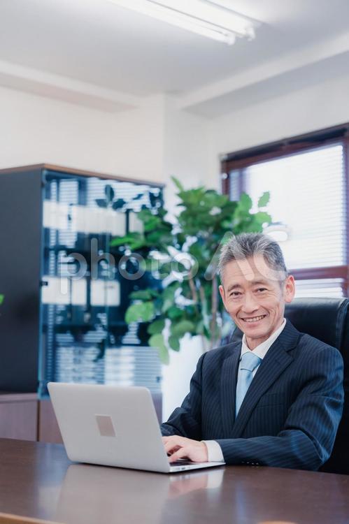 パソコンで仕事をする社長 売上,中年,期末の写真素材