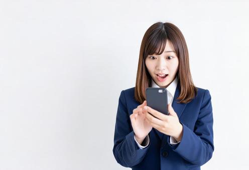 スマホの通知に驚く若い日本人の女性 スマホの通知に驚く若い日本人の女性の写真