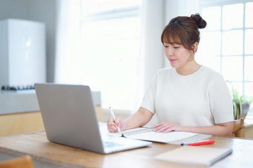 ルーズリーフに書いているお団子ヘアの女性 女性,ノートパソコン,見るの写真素材