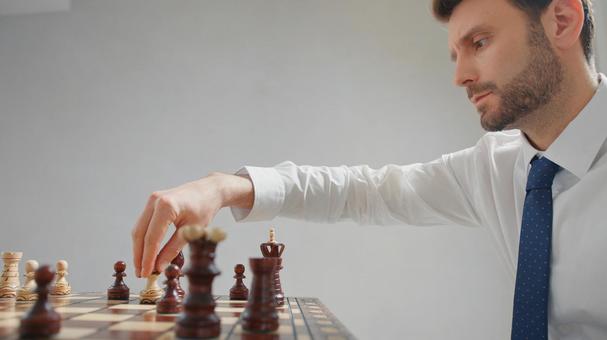 チェスの駒を持つ横向きのネクタイをした男性(グレー背景) チェスの駒を持つ横向きのネクタイをした男性(グレー背景) チェス,男性,30代の写真素材