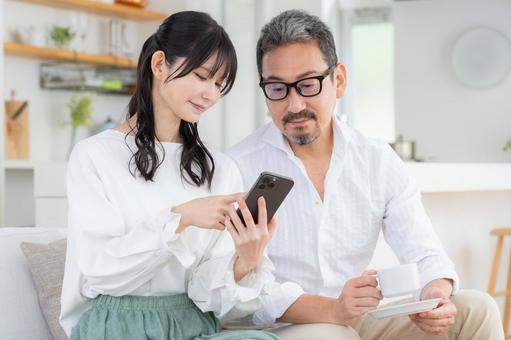 リビングでスマホを見るミドルの夫婦 リビングでスマホを見るミドルの夫婦 夫婦,家族,ミドルの写真素材