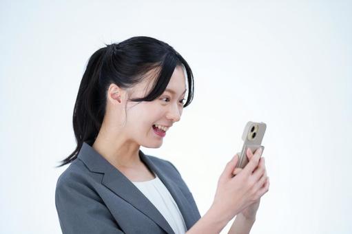 女性がスマートフォンを見ながら笑う 女性,スマートフォン,持つの写真素材