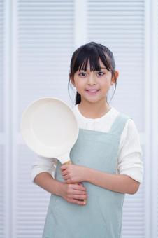 楽しそうにフライパンを掲げるクッキングシーン 女の子,フライパン,持つの写真素材