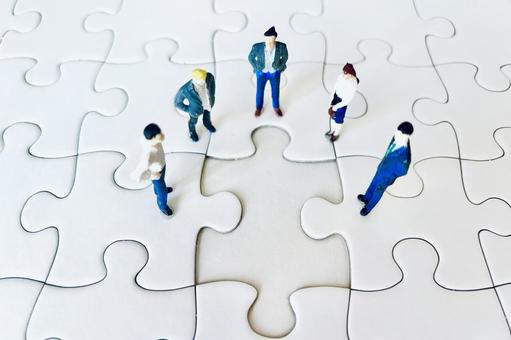 ジグソーパズルと会議するビジネスマンの写真