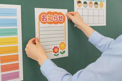 学校の教室に掲示物を貼る先生の手元 学校の教室に掲示物を貼る先生の手元の写真