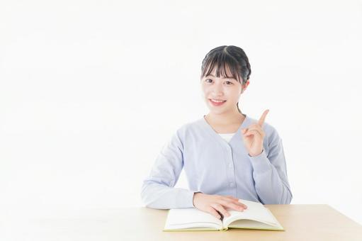 勉強をしながら指を指す若い女子学生 勉強をしながら指を指す若い女子学生の写真