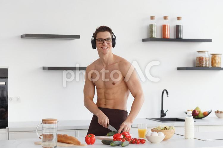 ヘッドホンをして野菜を切る男性 男性,マッチョ,料理の写真素材