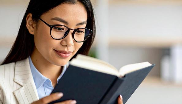 分厚い法律書を読む眼鏡の行政書士の女性 分厚い法律書を読む眼鏡の行政書士の女性の写真