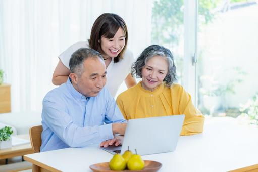 リビングでパソコンを見る親子 リビングでパソコンを見る親子 シニア,夫婦,子供の写真素材
