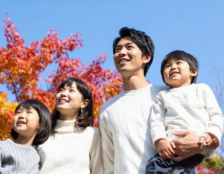 青空の下で秋の紅葉を仲良く鑑賞する家族 青空の下で秋の紅葉を仲良く鑑賞する家族の写真