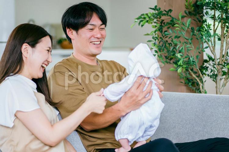 ソファで赤ちゃんを抱く男女 赤ちゃん,育児,新婚の写真素材