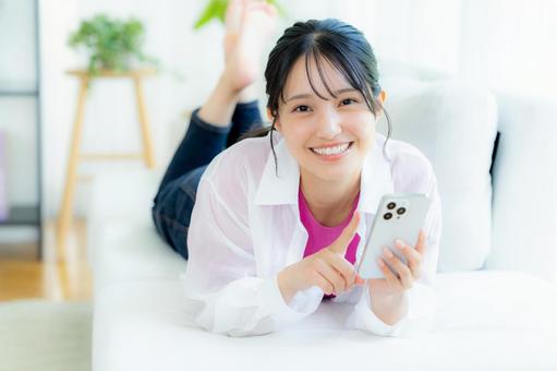 部屋でスマホを操作する若い女性 部屋でスマホを操作する若い女性 スマホ,若い女性,笑顔の写真素材