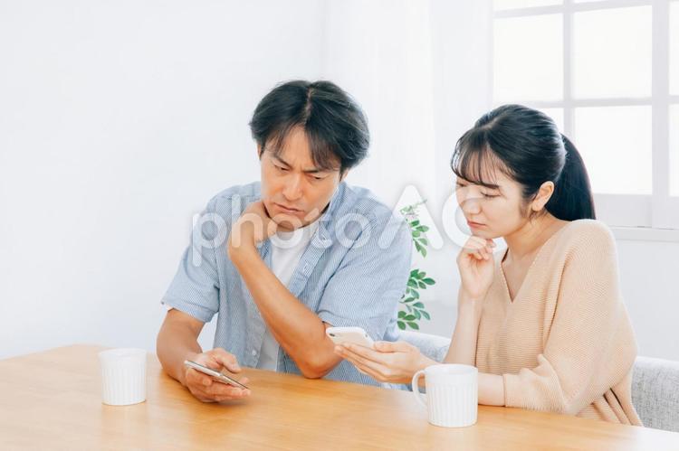 スマホを見る夫婦（困る） スマホ,夫婦,困るの写真素材