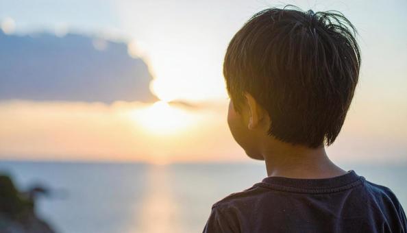夕焼けの空を見つめる日本人の少年 夕焼けの空を見つめる日本人の少年の写真
