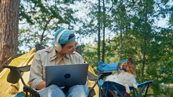 ノートPCで作業をしながら犬を見る 男性,外国人,犬の写真素材