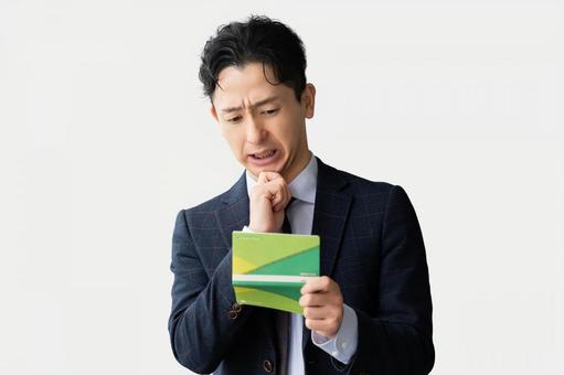 通帳を見て考える男性ビジネスマン 通帳を見て考える男性ビジネスマン 男性,ビジネス,ビジネスマンの写真素材