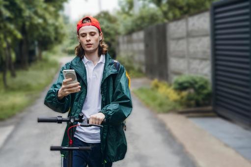 住宅街でスマートフォンを使うフードデリバリーの男性 配達,フードデリバリー,デリバリーの写真素材