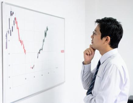 チャートを見て検討する男性ビジネスマンの写真