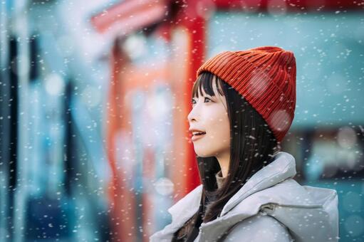 雪の降る冬の街角に立つ笑顔の女性 冬,雪,女性の写真素材