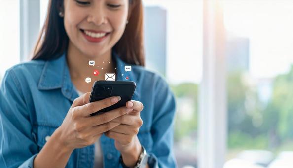 携帯電話でソーシャルメディアを楽しむ女性 携帯電話でソーシャルメディアを楽しむ女性の写真