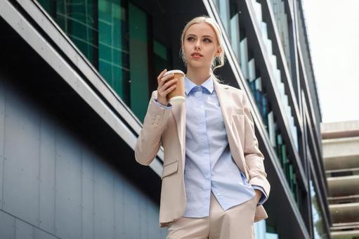 オフィスビルの外に居るコーヒーを持ったビジネスウーマン ビジネスウーマン,ビジネス,女性の写真素材