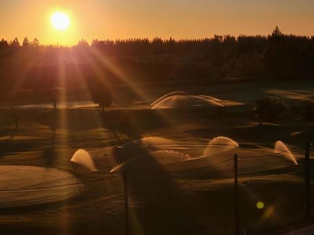 朝日とスプリンクラー 荒川,サイクリングロード,夜明けの写真素材