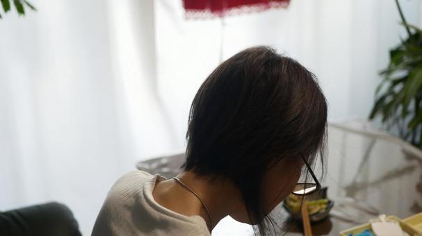 テーブルに向かう女性の後頭部 テーブルに向かう女性の後頭部の写真