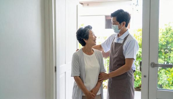 見守り訪問で高齢者住宅を訪問する男性の写真