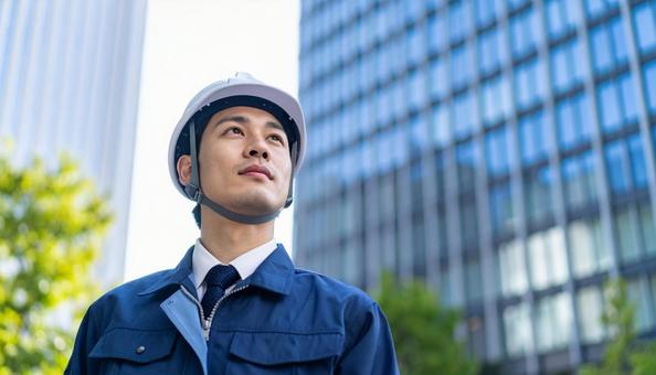 ビル背景に斜め上を見る若い男性建設作業員 ビル背景に斜め上を見る若い男性建設作業員の写真