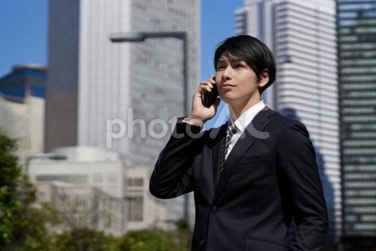 オフィス街で電話をするビジネスマン ビジネスマン,男性,スマートフォンの写真素材