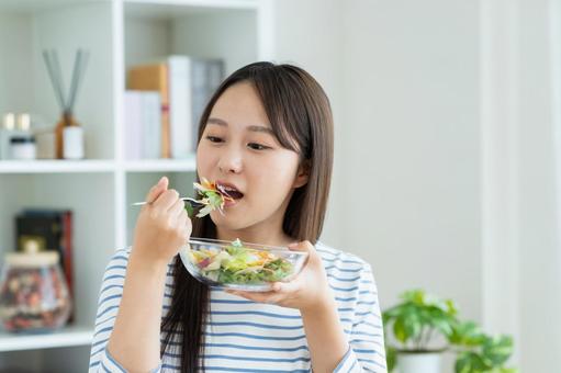 サラダを食べる若い女性 サラダを食べる若い女性の写真
