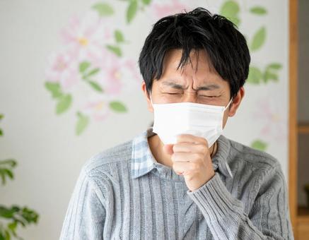 マスクを着用して咳をするの男性 マスクを着用して咳をするの男性の写真