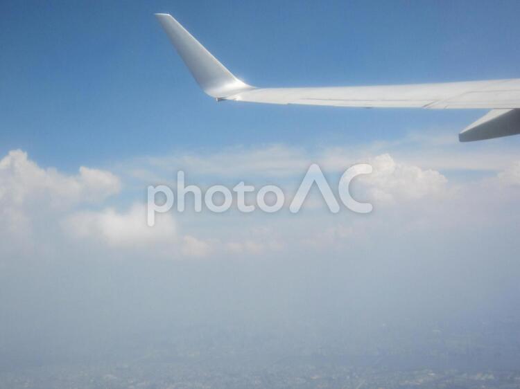 かなり上空。下には、かすんでいる街が・・。 飛行機,飛行場,翼の写真素材