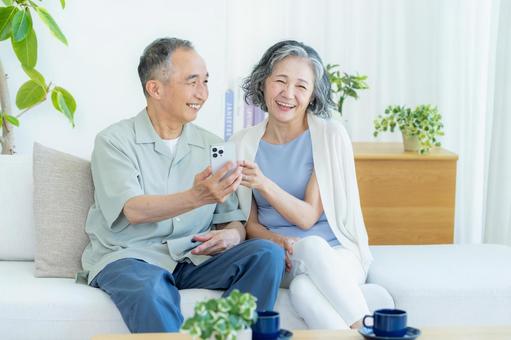 リビングでスマホを見るシニア夫婦 リビングでスマホを見るシニア夫婦 スマホ,シニア,笑顔の写真素材