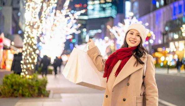 紙袋を手にする女性とイルミネーション 紙袋を手にする女性とイルミネーションの写真