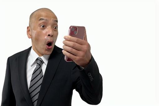 スマホを見て驚いて目を見開くスーツ男性 スマホを見て驚いて目を見開くスーツ男性 ビジネス,男性,スーツの写真素材