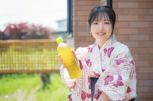 笑顔でお茶を差し出す浴衣女性 笑顔でお茶を差し出す浴衣女性 水分補給,お茶,ペットボトルの写真素材