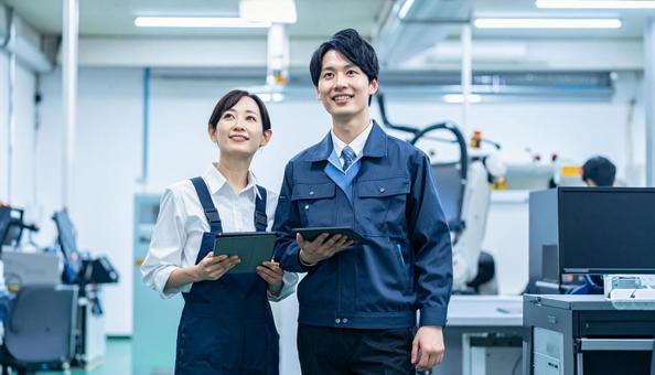 工場でタブレットで製品を検査する作業員 工場でタブレットで製品を検査する作業員の写真