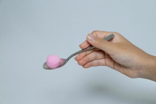 スプーン上のピンク色の丸いポンポン玉と手 ポンポン玉,スプーン,手の写真素材