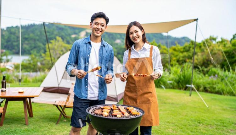 バーベキューで串を持って笑顔の男女 バーベキュー,キャンプ,アウトドアの写真素材