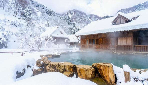 雪の積もる山中の湯気が立ち上る露天風呂 雪の積もる山中の湯気が立ち上る露天風呂の写真