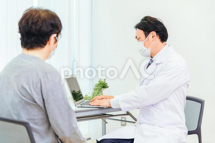 パソコンで診察するマスク姿の男性医師 医者,医師,健康診断の写真素材