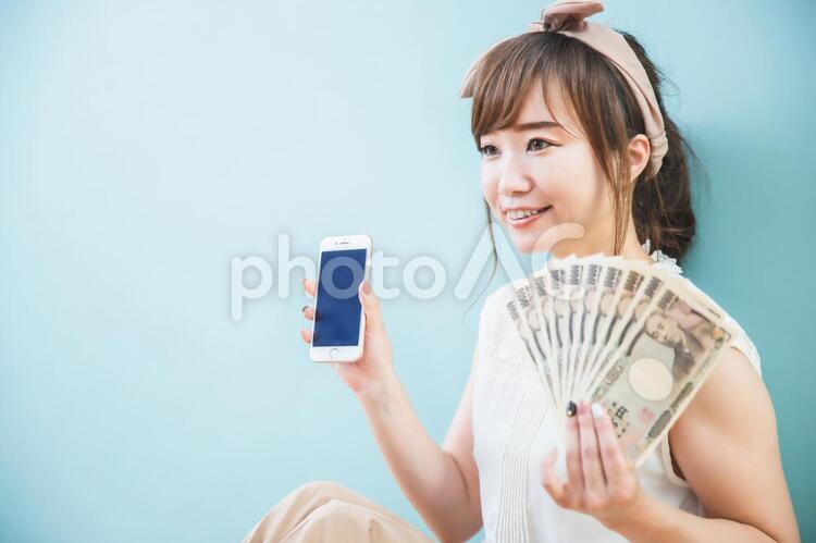 スマホとお金を持つ女性 副業,サイドビジネス,副収入の写真素材