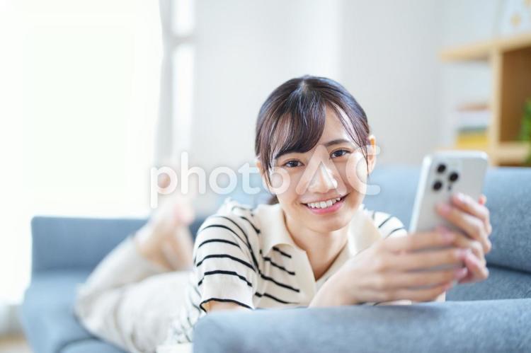 スマホを持ちカメラ目線の女性 女性,スマートフォン,持つの写真素材