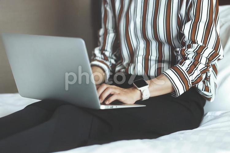 室内でベッドに座ってラップトップを使用する女性 パソコン,ラップトップ,ノートパソコンの写真素材