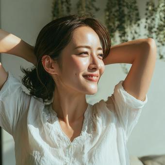 朝日を浴びて伸びをする女性の写真