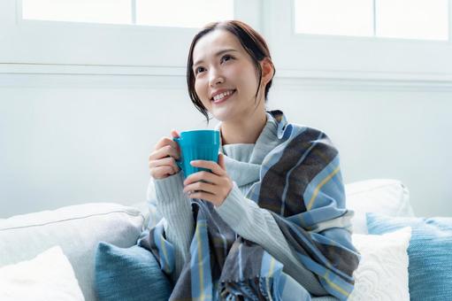 ソファでカップを持つ女性 リラックス,おうち時間,女性の写真素材