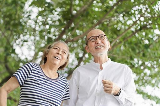 คู่สามีภรรยาสูงอายุเดินเล่นในสวนสาธารณะด้วยรอยยิ้ม, พลเมืองอาวุโส, สามีภรรยา, ใบหน้าที่ยิ้มแย้ม, JPG