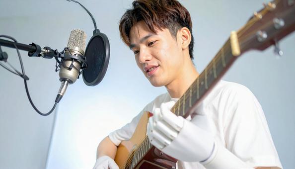 義手の若者がギターを弾く 義手の若者がギターを弾くの写真