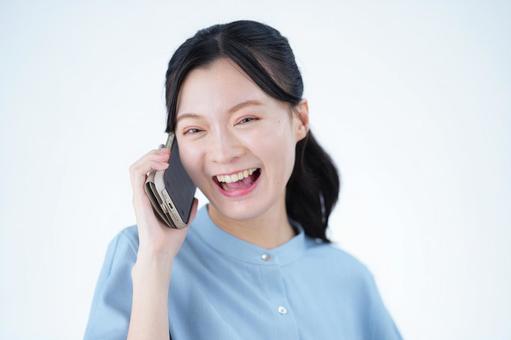 女性が電話をしながら笑う 女性,スマートフォン,持つの写真素材